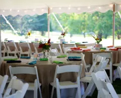 A tented reception with burlap tablecloths and colorful napkins.